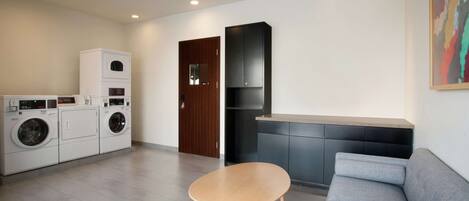 Una sala de estar moderna con un sofá gris, una mesa de centro de madera y una cocina integrada con armarios oscuros.