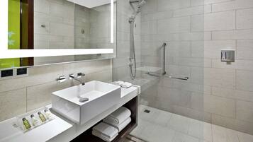 A modern bathroom with a large mirror, two sinks, a shower, and a towel rack.