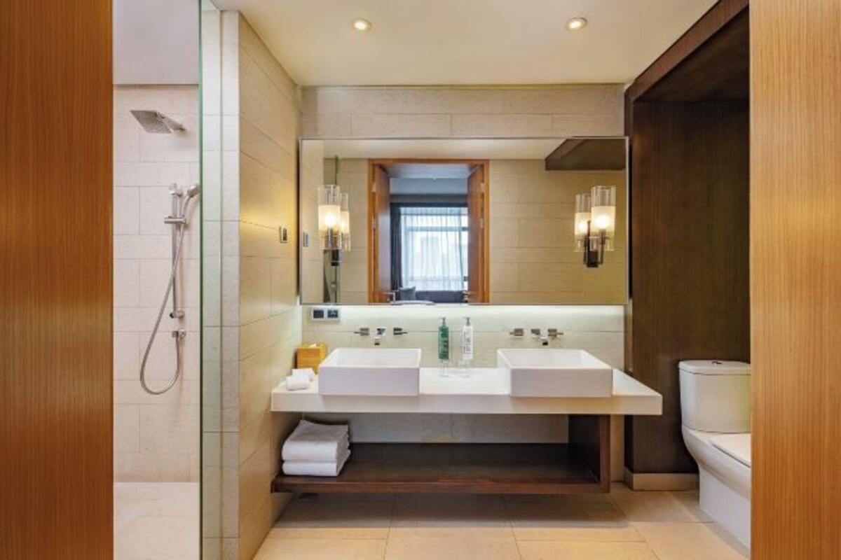A modern bathroom with a double sink vanity, a glass shower enclosure, and a toilet.