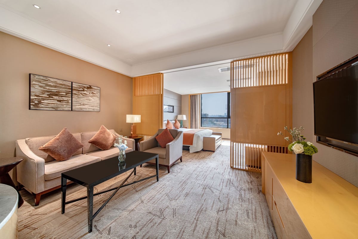 A modern hotel room with a sofa, coffee table, and a TV.