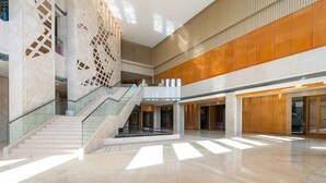 A spacious lobby with a central staircase, high ceilings, and modern architectural design.
