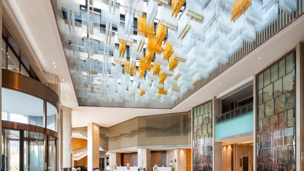 A spacious lobby with a high ceiling, modern furnishings, and a reception desk.