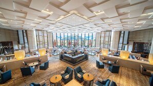 A spacious lobby with a central seating area, large windows, and a chandelier.