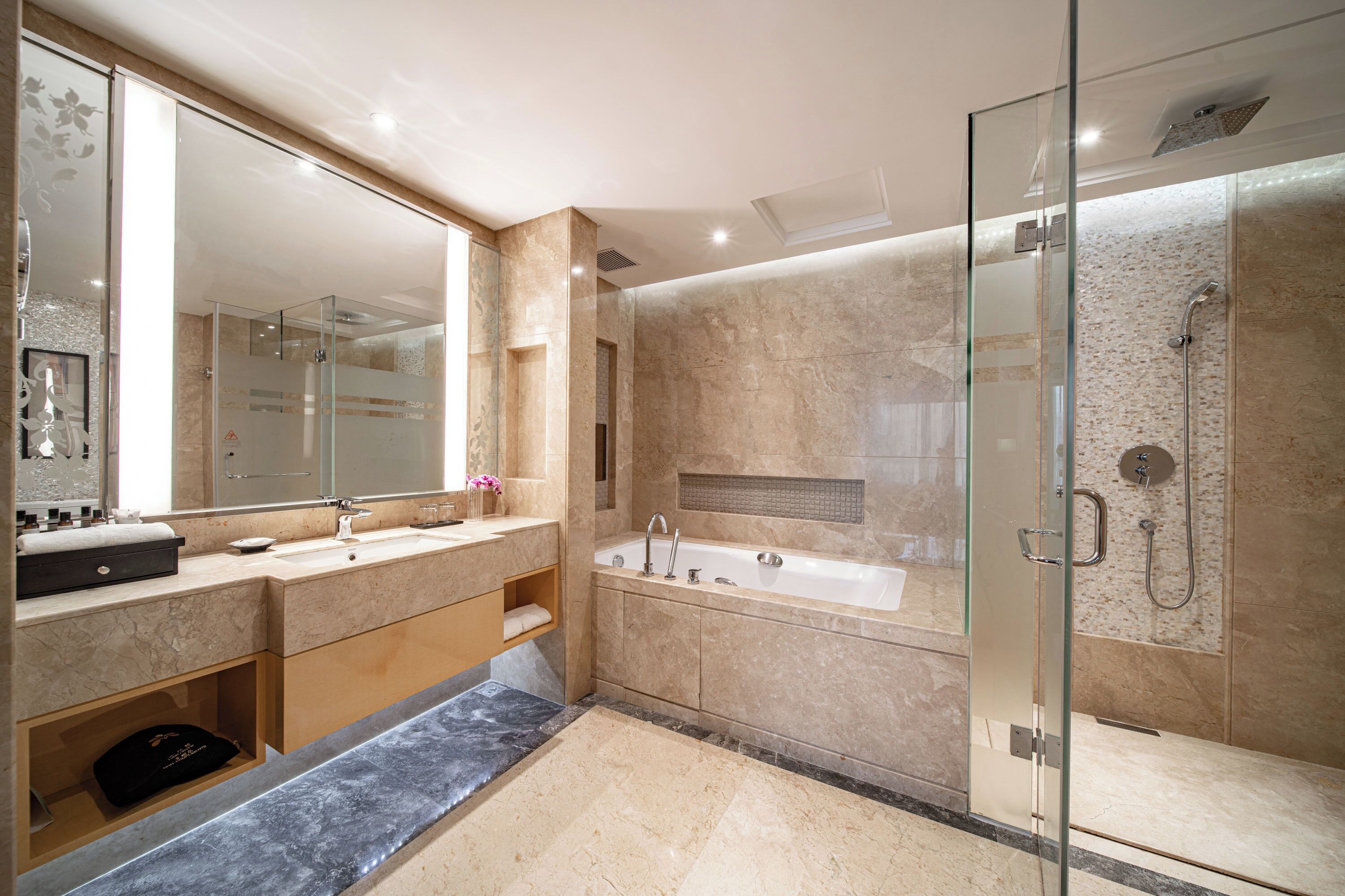 Un baño moderno con un espejo grande, dos lavamanos, una bañera y una zona de ducha con mampara de vidrio.