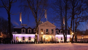 Edificio cubierto de nieve con fachada iluminada y jardín nevado.
