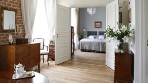 Un dormitorio con cama, cómoda, silla, mesita de noche, lámpara y un jarrón con flores.