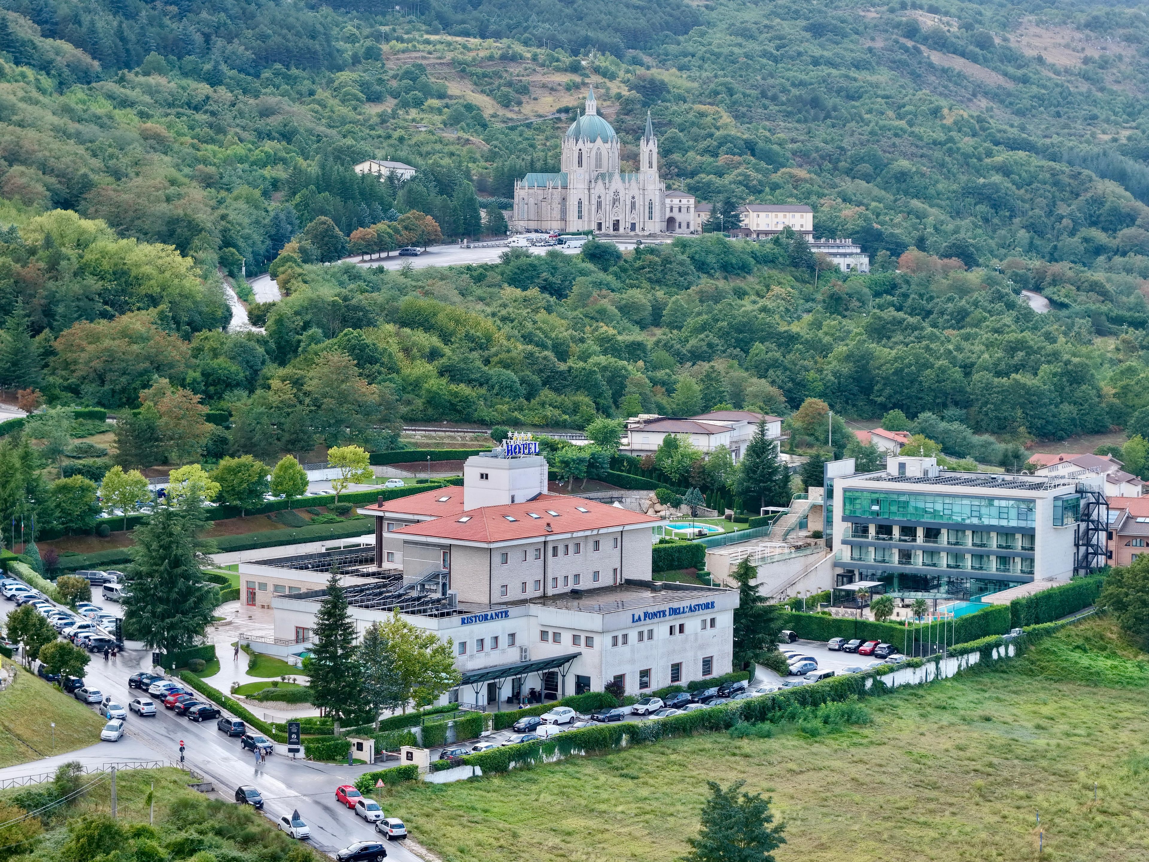 A hotel with a parking lot, a restaurant, and a large church in the background.