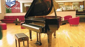 A grand piano in a hotel lobby with a red sofa and a bar area in the background. - La Fonte dell'Astore (Castelpetroso)