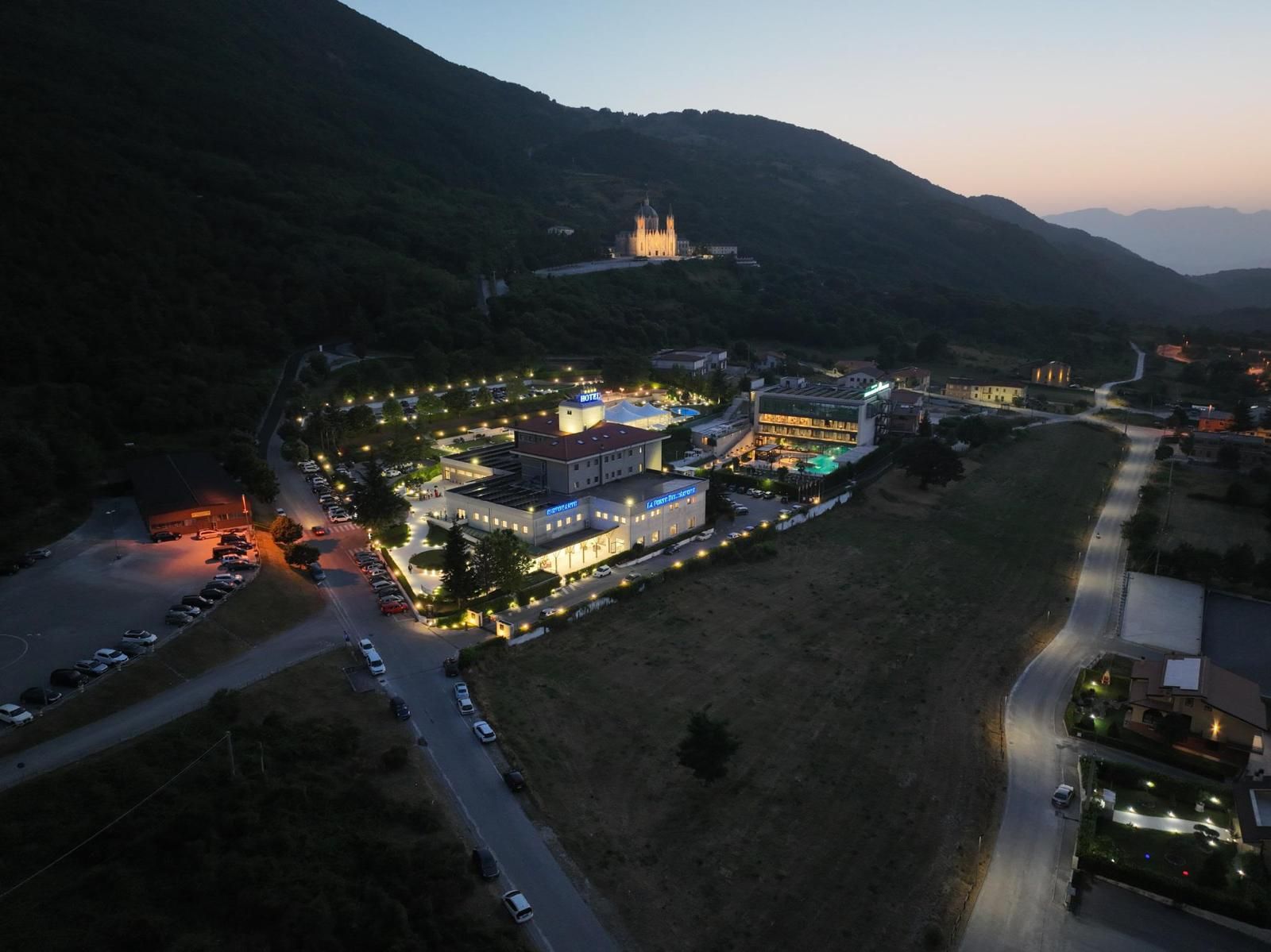 A hotel complex with multiple buildings, parking areas, and a prominent church in the background.