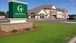 A GrandStay Hotel & Suites sign with a modern building in the background.
