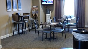 A dining area with a TV mounted on the wall, a water dispenser, and a trash can.