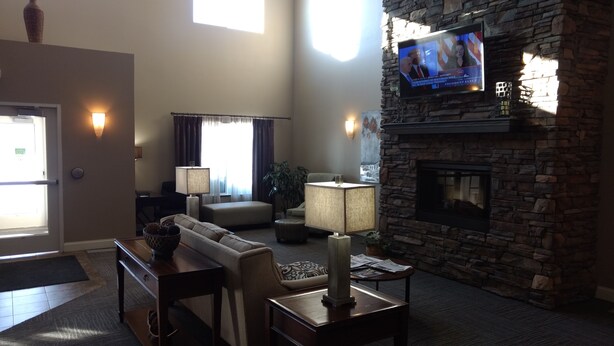 A modern living room with a stone fireplace, comfortable seating, and a television mounted on the wall.