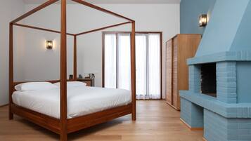 Ein Bett mit Baldachin, ausgestattet mit weißen Leinen, Holzboden, eine blaue Akzentwand und ein Kamin.