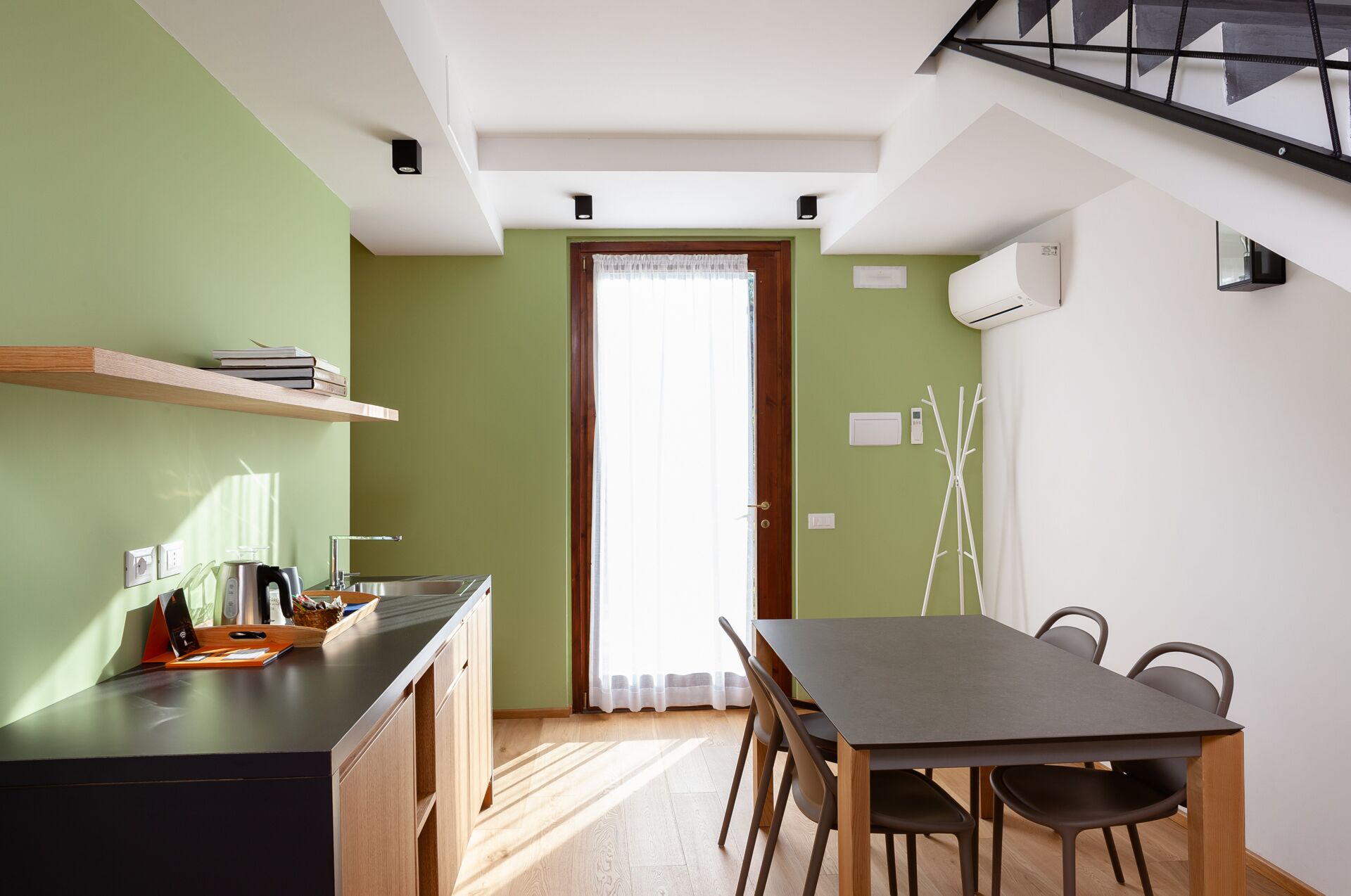 Una cocina moderna con zona de comedor, que incluye una mesa y sillas de madera, cocina empotrada y una ventana con cortinas.