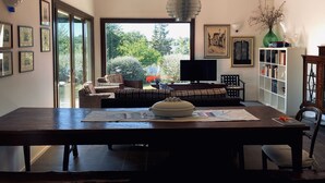A dining area with a wooden table, chairs, a television, and a bookshelf. - A3Passi Agriturismo tra gli Ulivi (Ancona)