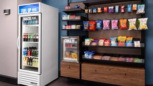 Máquina expendedora con aperitivos y un refrigerador con la etiqueta 'SNACKS TO-CO' y 'CHILL OUT'.