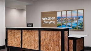 Una recepción con un cartel que dice 'bienvenido a Hampton' y una insignia de 'Hilton Honors'.