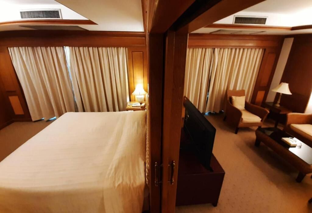 Ein Hotelzimmer mit einem großen Bett, zwei Sesseln, einem kleinen Tisch und einem Schreibtisch mit einer Lampe.