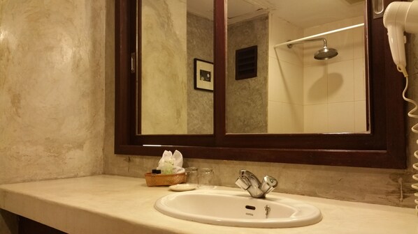 A bathroom with a large mirror, a sink, and a shower area.