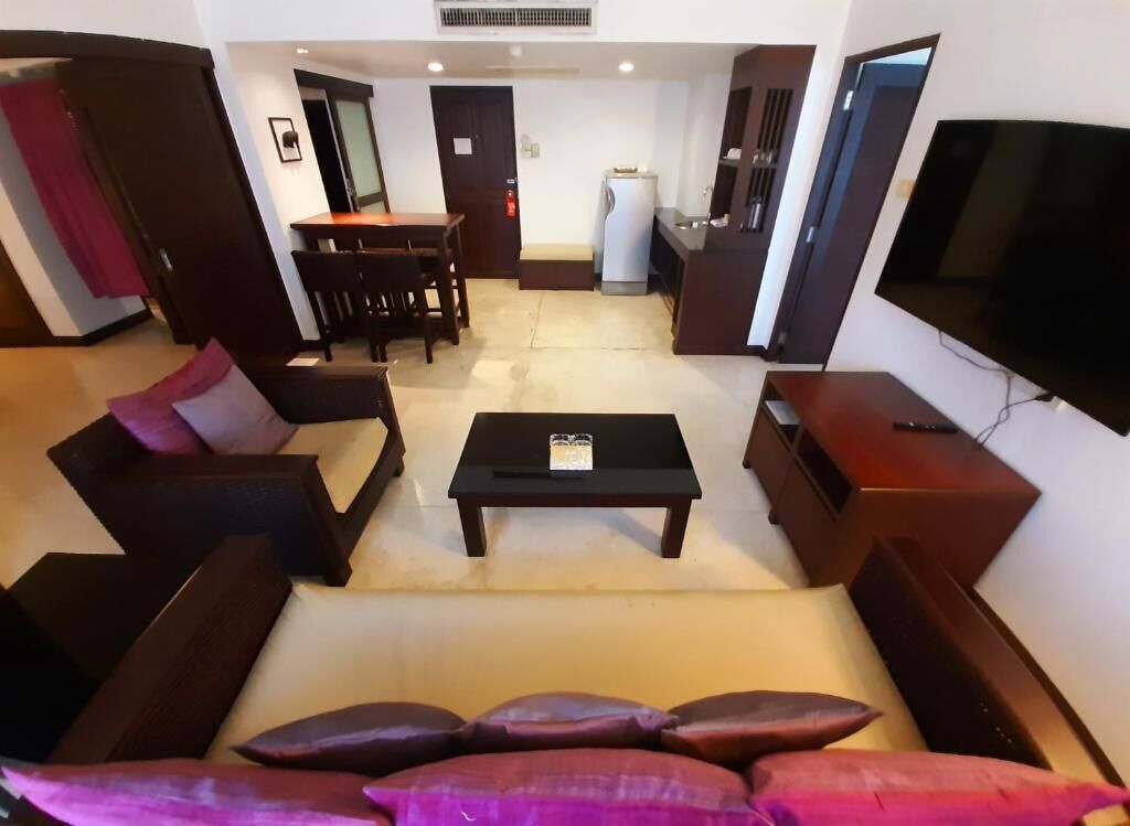 A living room with a sofa, a coffee table, a TV, and a dining area with a table and chairs.