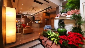 A modern hotel lobby with a reception desk, seating area, and a staircase leading to upper floors. - Grand Hotel (Pattaya)