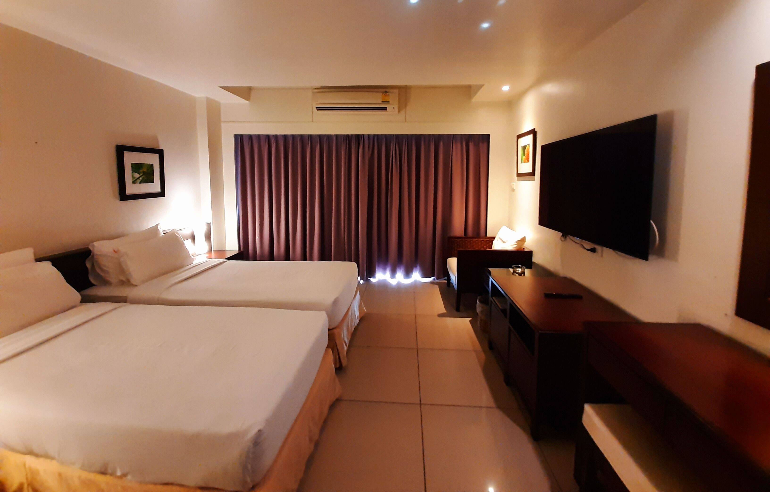 Une chambre d’hôtel avec deux lits, une télévision, un bureau et un rideau.