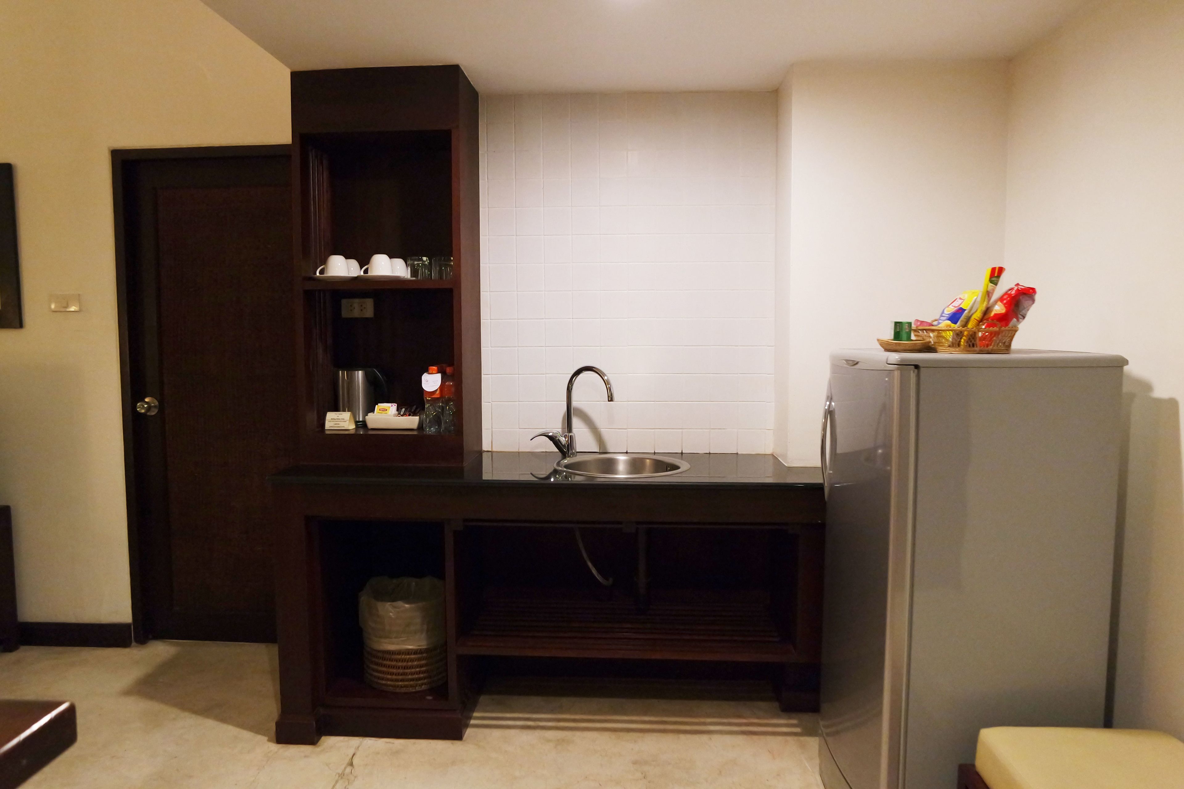 A compact kitchen with a sink, a refrigerator, and a cabinet with dishes.