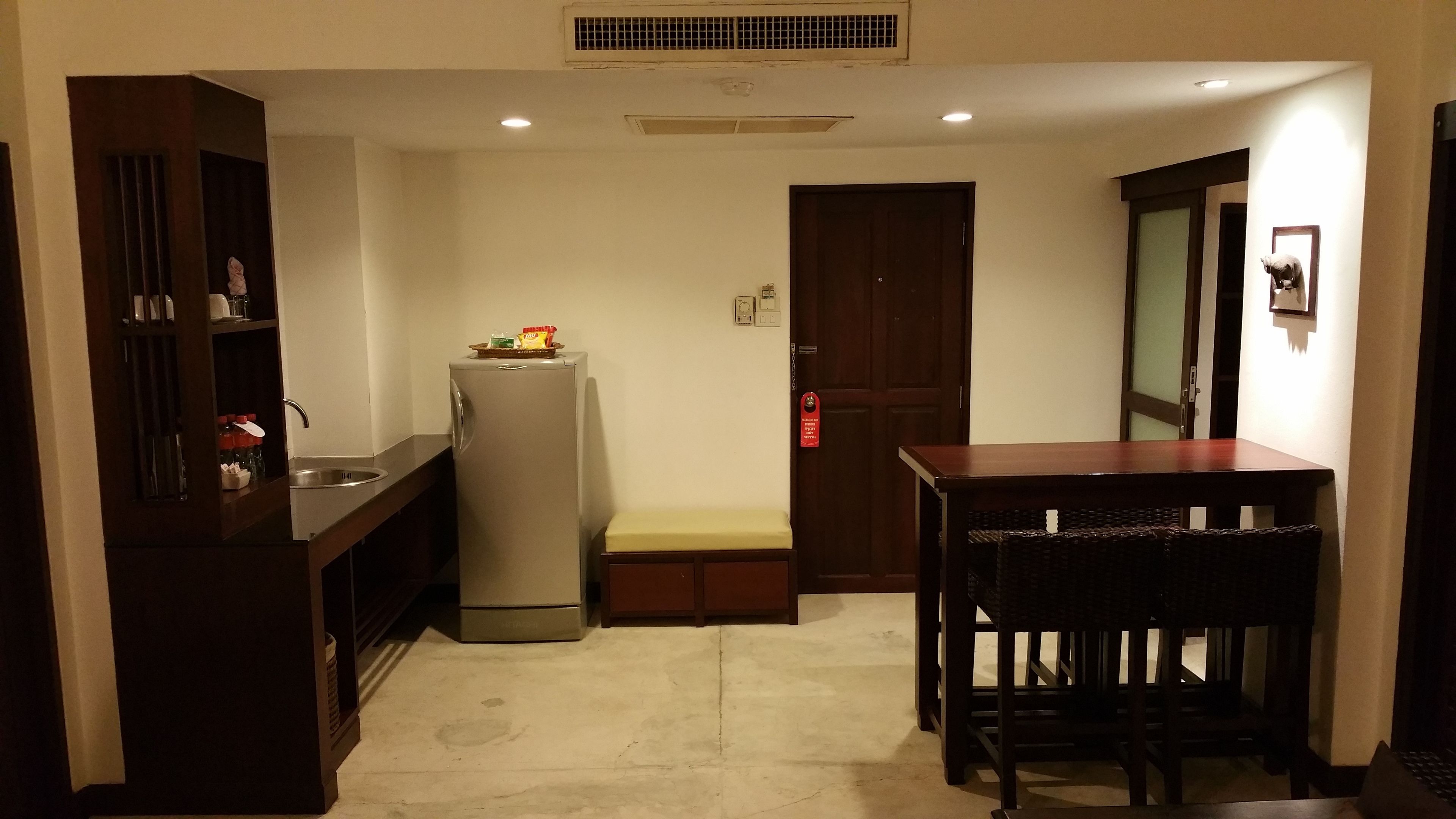 A compact kitchen with a refrigerator, sink, and wooden cabinets.