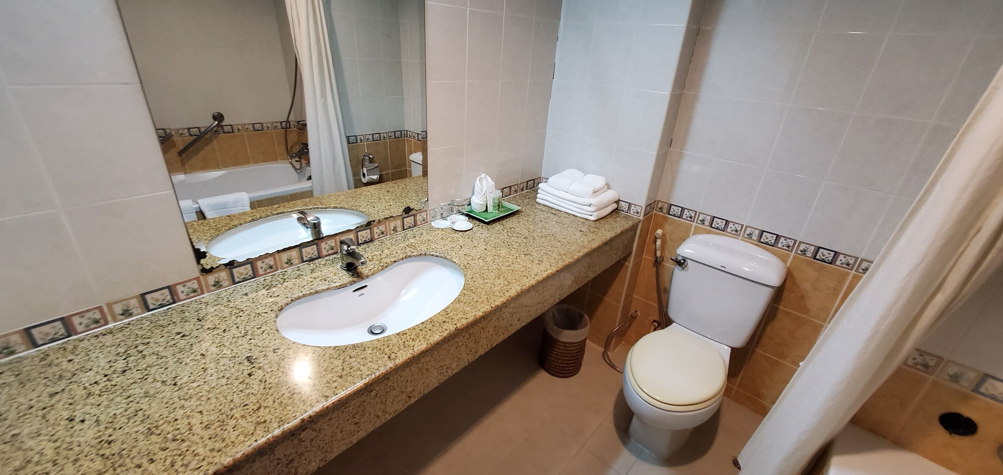A bathroom with a granite countertop sink, a toilet, and a mirror.