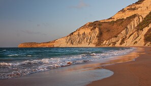 Une plage avec une falaise rocheuse et des vagues.