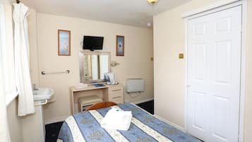 Habitación de hotel con cama, escritorio, computadora, lavamanos y puerta.