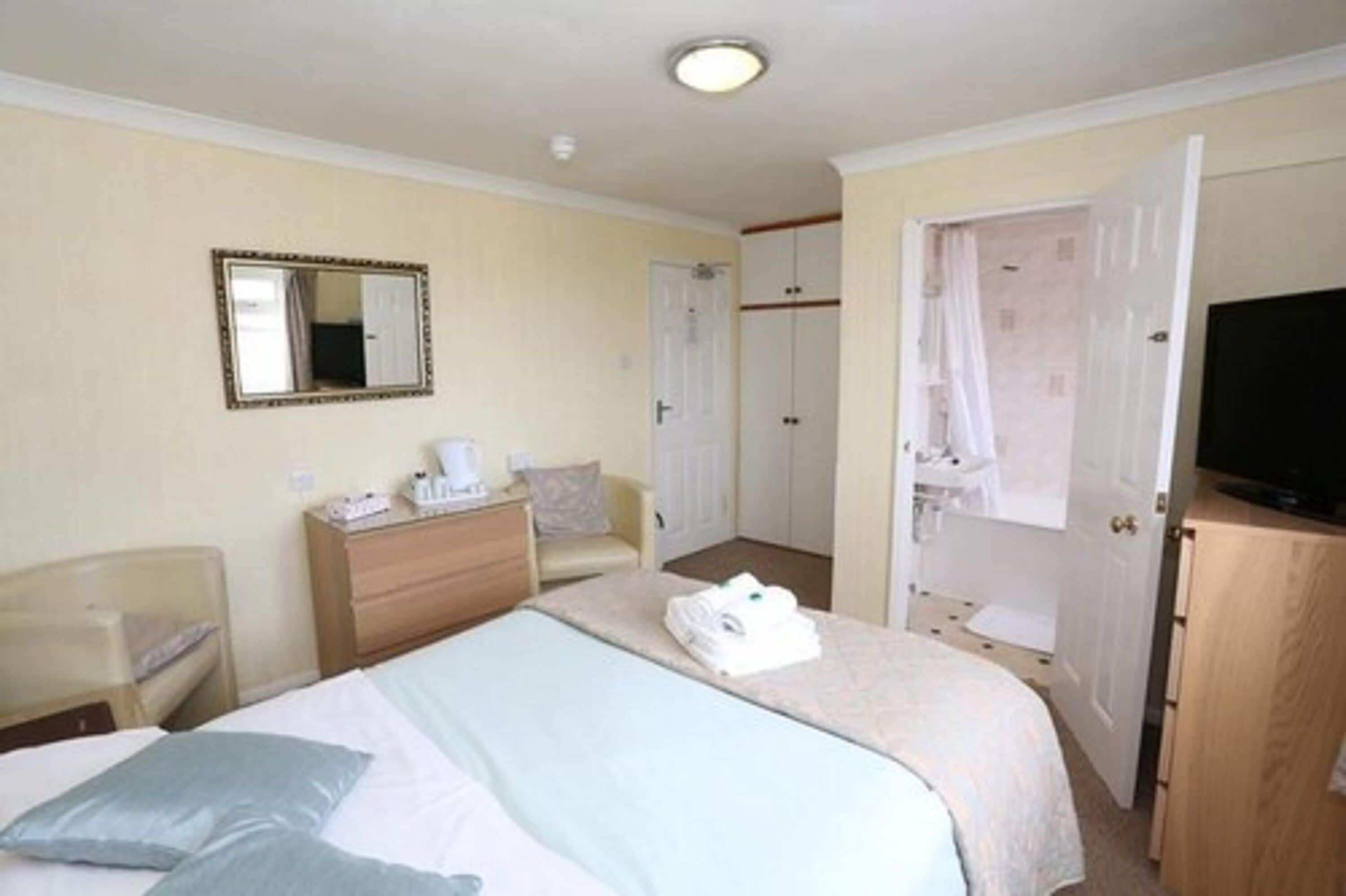 A hotel room with a bed, a dresser, a chair, a television, and a wardrobe.