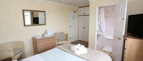 Ein Hotelzimmer mit Bett, Schminktisch, Sessel, Fernseher und Kleiderschrank.