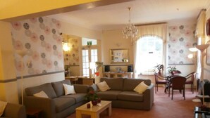 A living room with a sofa, coffee table, and a dining area with chairs and a table. - Dorset Hotel (Ryde)
