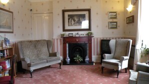 A traditional living room with a fireplace, a sofa, and two armchairs. - Dorset Hotel (Ryde)
