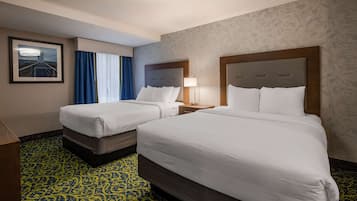 A hotel room with two beds, a nightstand, a lamp, a framed picture on the wall, and a patterned carpet.