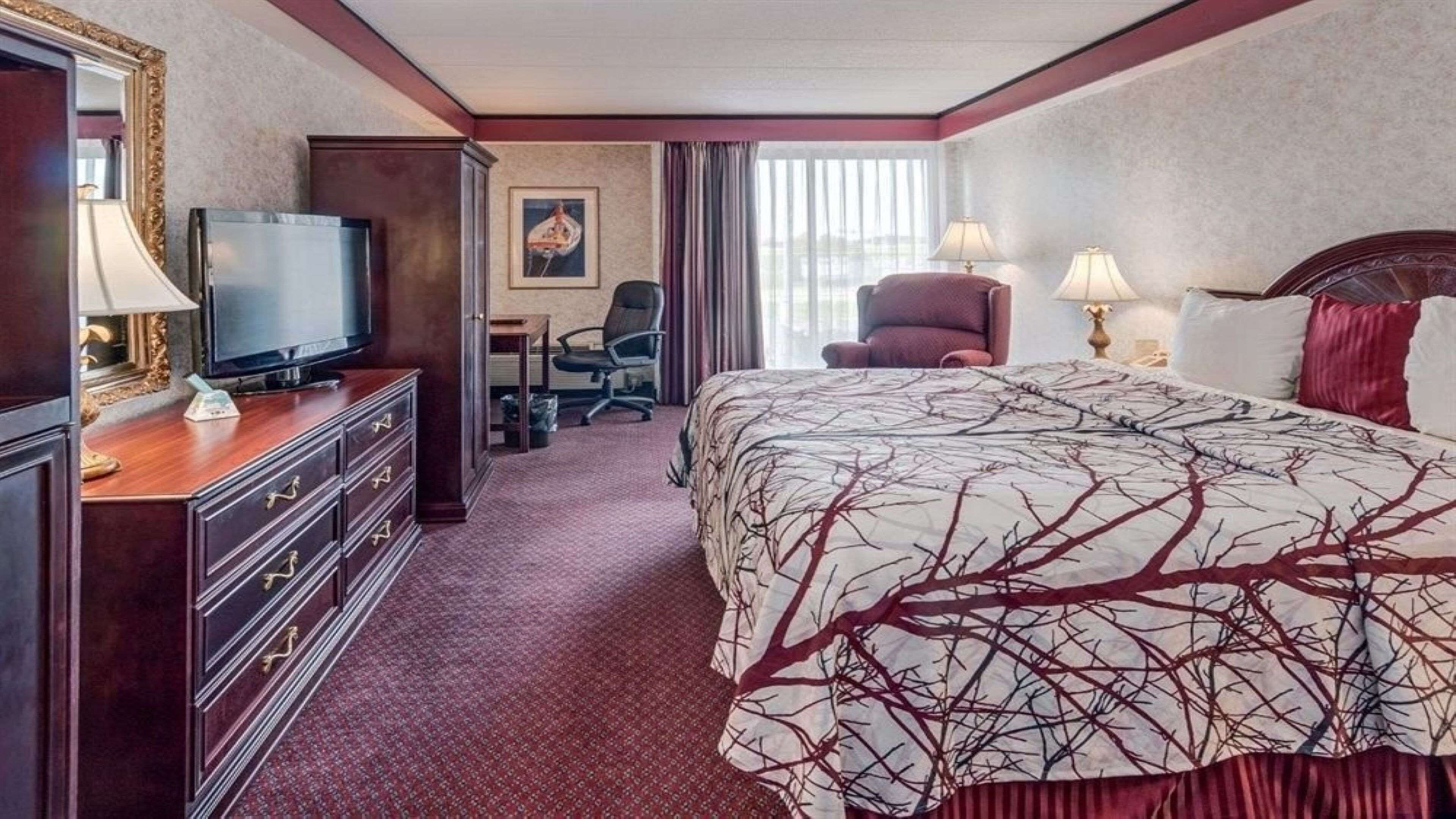 Una habitación de hotel con cama, televisión, escritorio y silla.