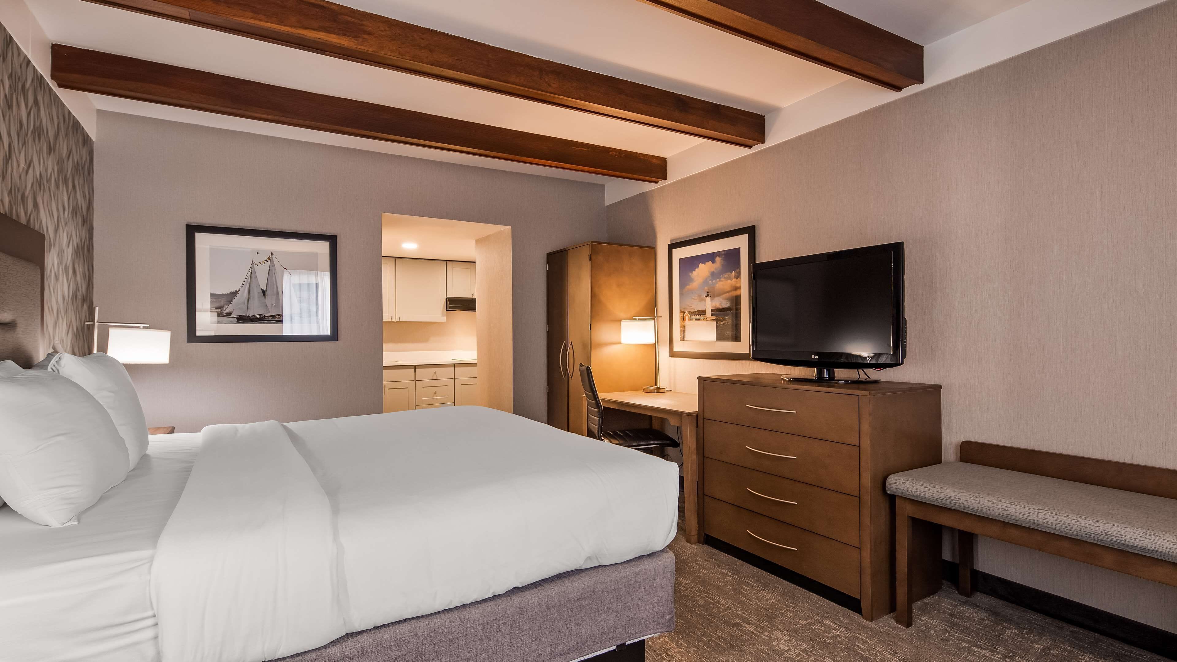 Habitación de hotel con cama, escritorio, televisión y banca.