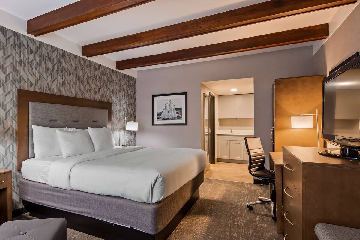 Una habitación de hotel con una cama grande, un escritorio, una silla y un televisor.