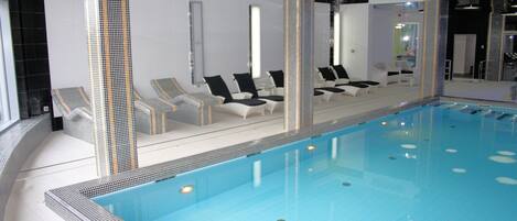 Een binnenzwembad, ligstoelen en redders ter plaatse