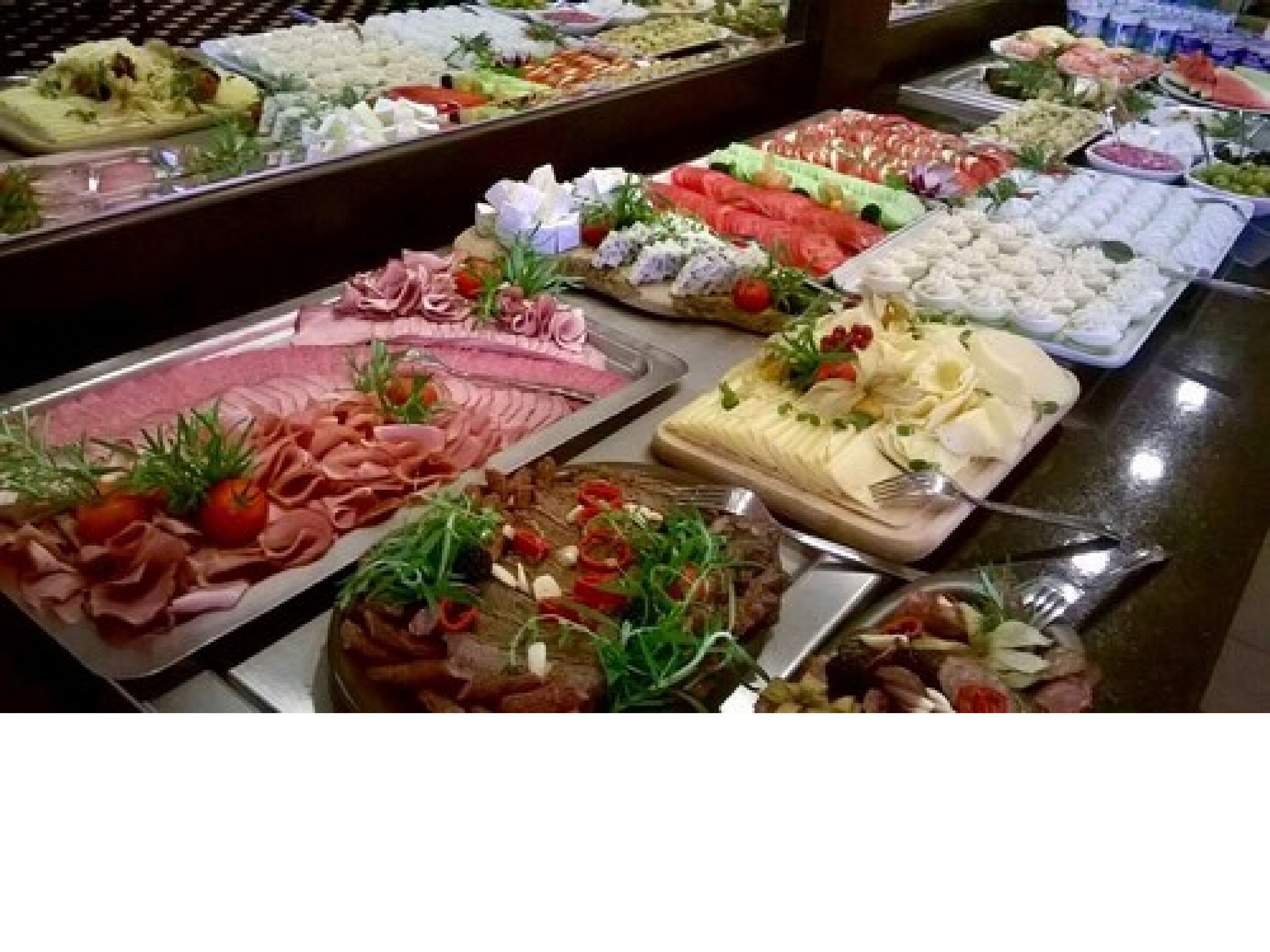Ein Buffet mit verschiedenen Speisen, darunter Fleisch, Käse und Salate.