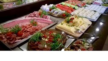 Ein Buffet mit verschiedenen Speisen, darunter Fleisch, Käse und Salate.