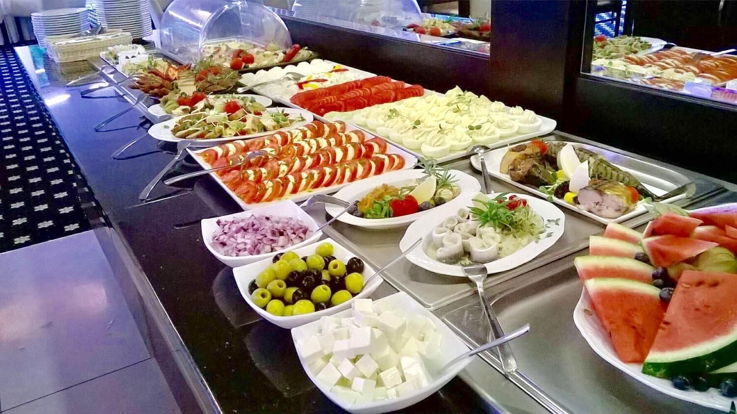 A buffet with various food items including salads, fruits, and cheeses.