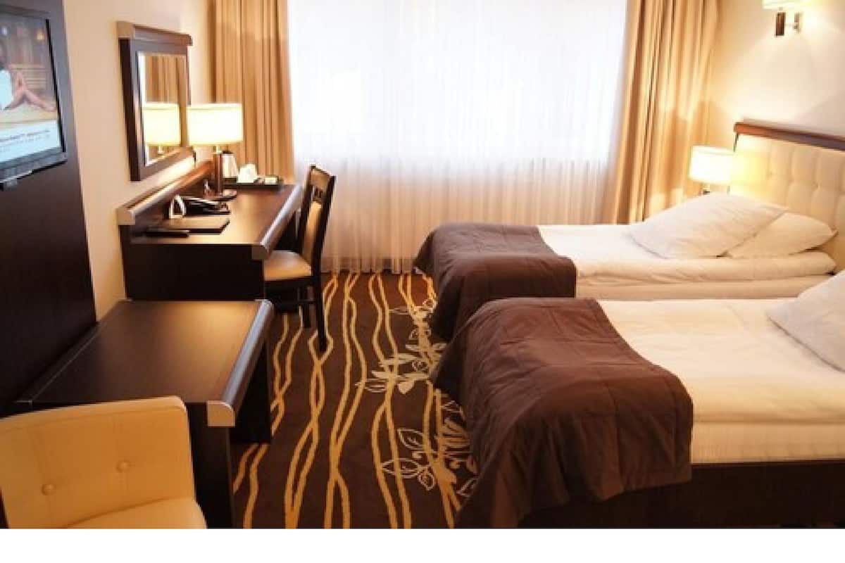 A hotel room with two beds, a desk, and a chair.