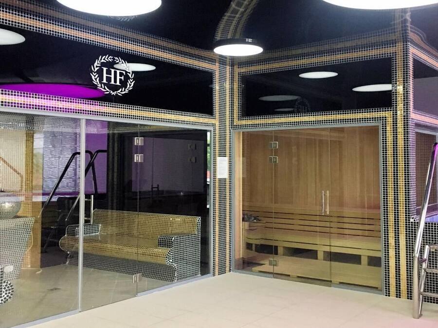 A spa with a glass entrance, a wooden bench inside, and a metal bench outside.