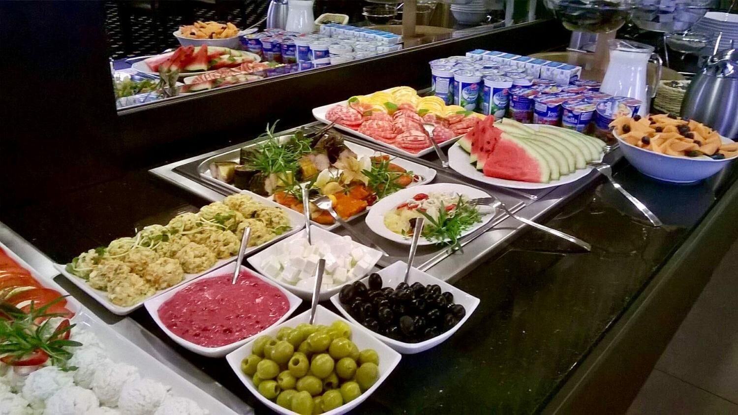 A buffet with various food options including salads, fruits, and dips.
