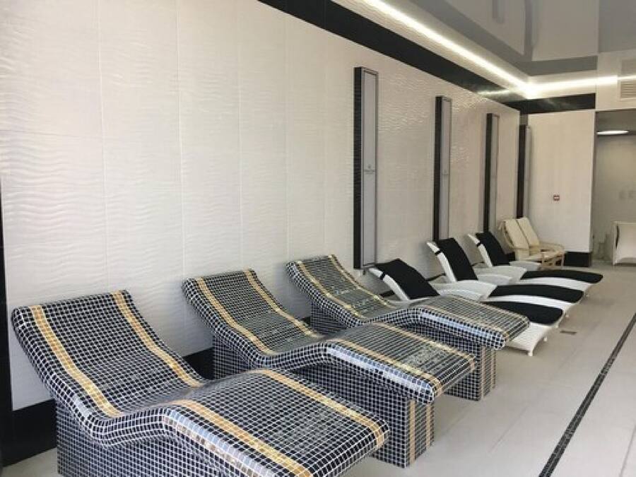 Eine Reihe von schwarz-weißen Liegestühlen in einem modernen Spa-Bereich mit weißen Wänden und Fliesenboden.