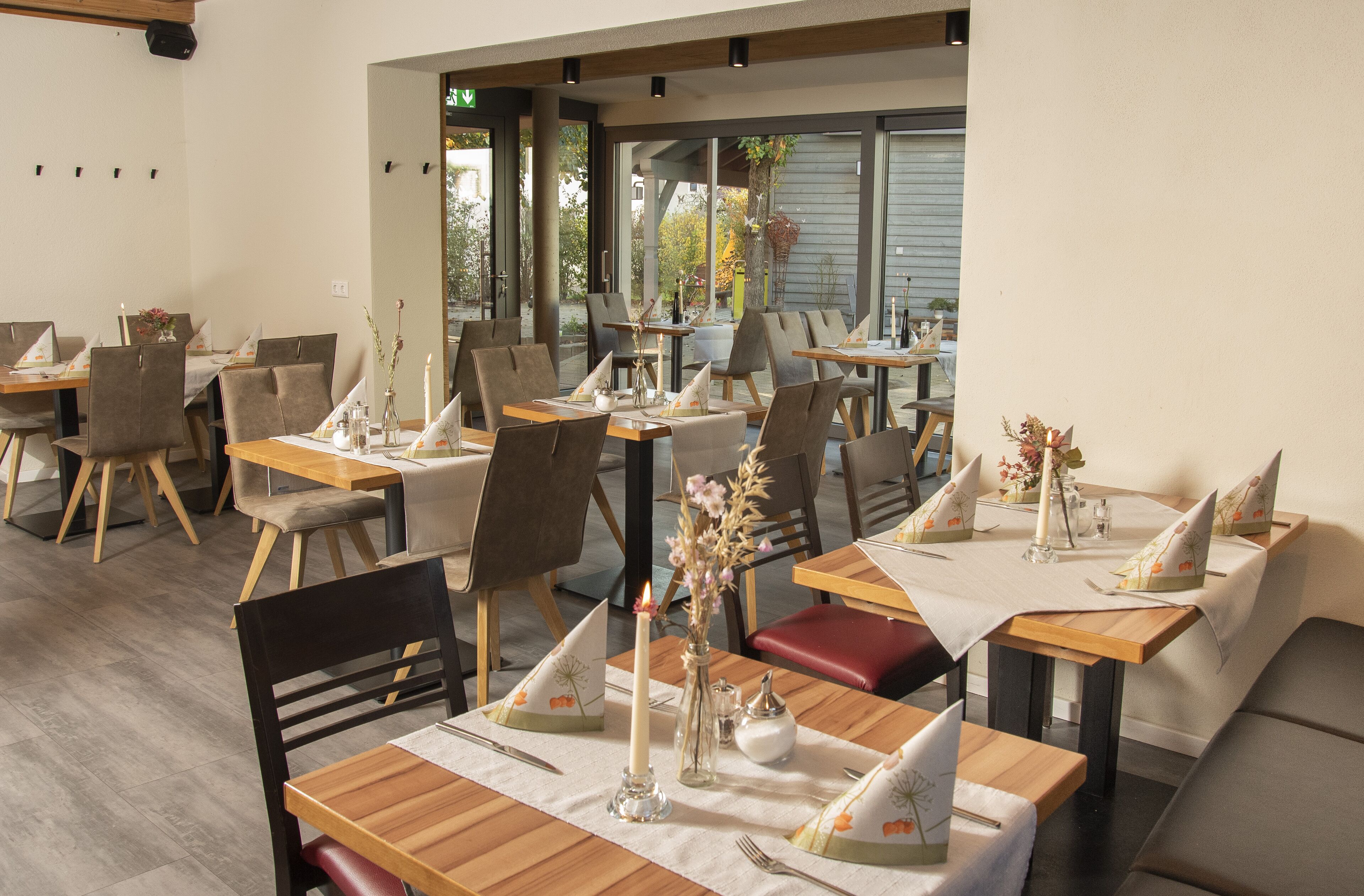 A restaurant with multiple tables, each set with chairs, candles, and floral centerpieces.