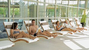 A sunroom with large windows, lounge chairs, and a tiled floor.