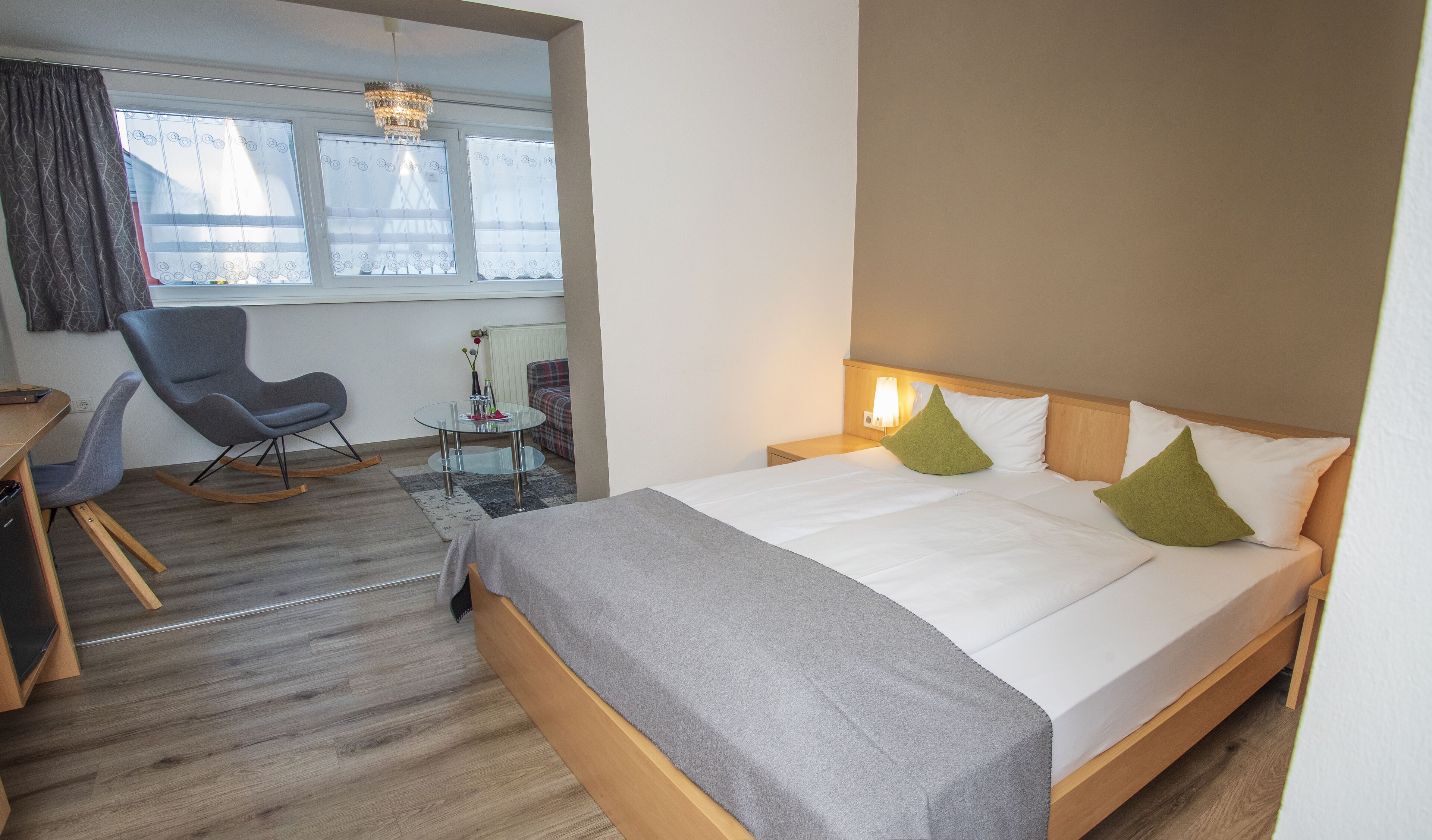 Une chambre d’hôtel avec un lit, un bureau, une chaise et une fenêtre avec des rideaux.